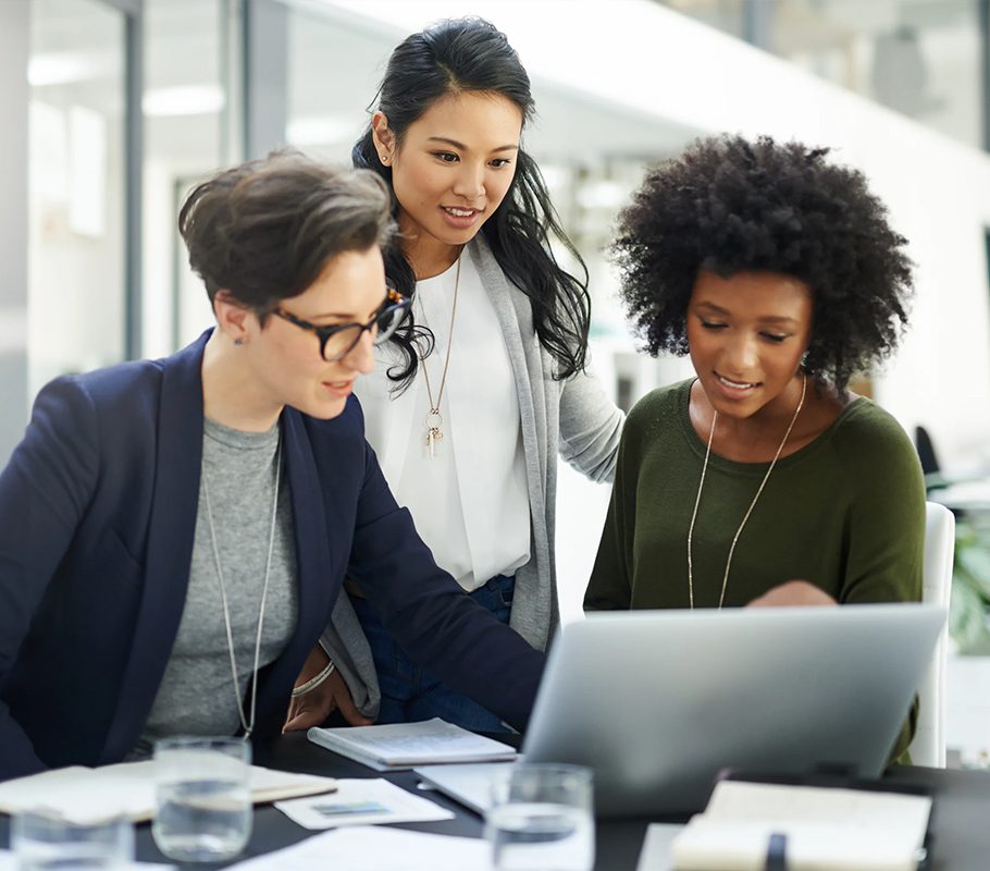 Three women are looking at a laptop together.